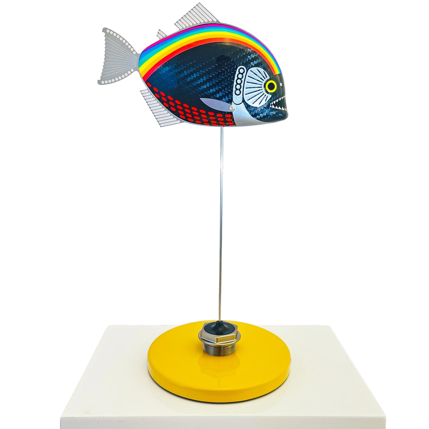 Carbon fibre piranha fish sculpture with NHS rainbow livery on a sandy base with F1 part