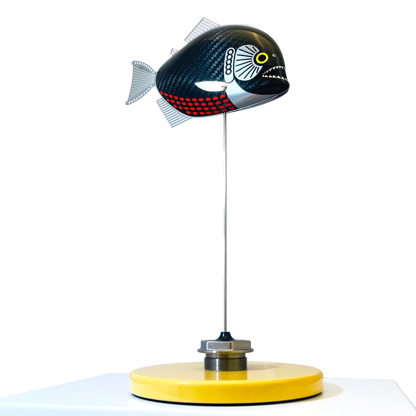 Carbon fibre baby piranha sculpture on a sandy base