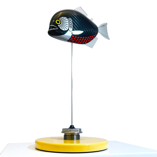 Carbon fibre baby piranha sculpture on a sandy base